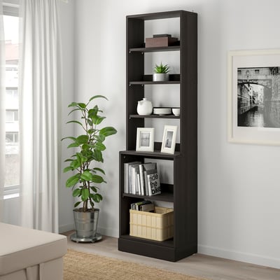 Dark wood HAVSTA shelf by window holds books, vases, pictures.