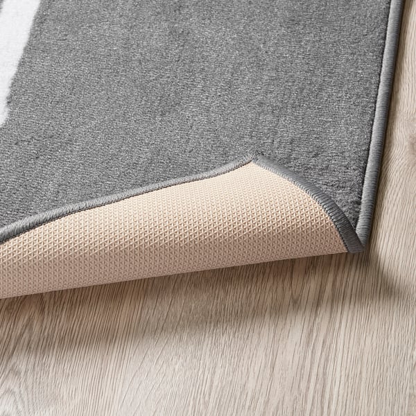 Grey hopscotch rug with rubber backing, placed on wooden floor, promoting childs motor skills.
