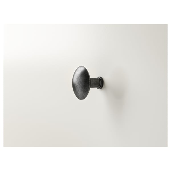 Single wall-mounted hook, dark finish. Attached vertically on smooth, light surface. Durable, minimalist design.