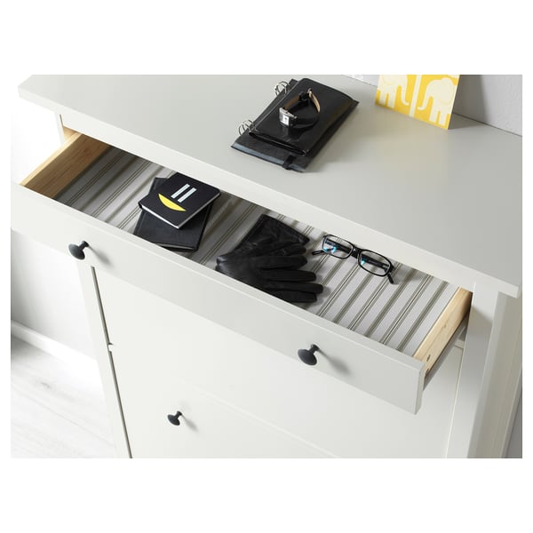 White shoe cabinet with wooden divider and gloves, organising space efficiently.