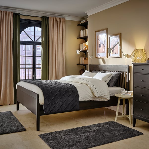 Modern bedroom with IDANÄS bed, white/gray bedding, gold lamp, city view, and art.