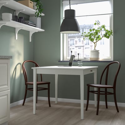 Modern compact home office with white drop-leaf table and brown chairs, green walls, and large window.
