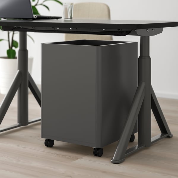 Black adjustable desk with smart lock drawer, castors, and pin board metal surface.