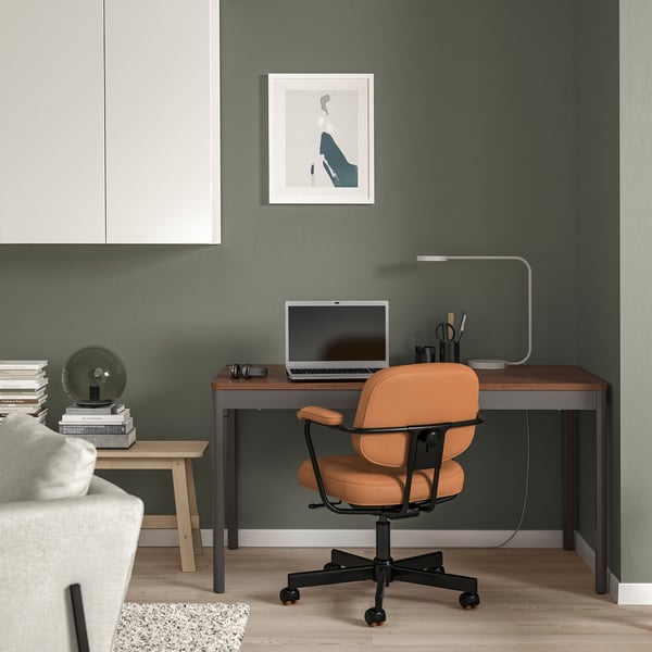 Modern home office with IDÅSEN desk, green room, orange chair, laptop, lamp, and decor.