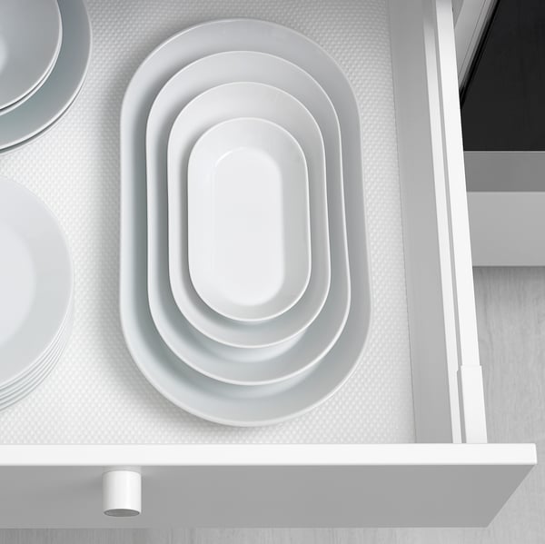 Stackable white porcelain dishes in drawer, saving space with nested design.