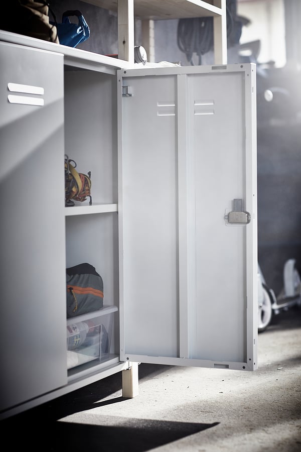 An open white IVAR storage cabinet with lockable doors and shelves, made of metal, standing indoors.