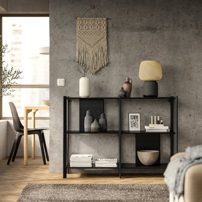 Modern living room JÄTTESTA black metal & bamboo shelf, displaying vases, books, and a yellow lamp. Concrete wall, wooden floor, and minimalist decor.