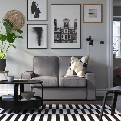 Grey KIVIK sofa, compact & cosy, low arms, patterned pillow, black/white art, chequered rug.