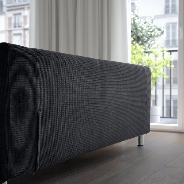 Dark sofa near large window. Soft fabric cover, removable for cleaning. Modern, comfortable design with metal springs.