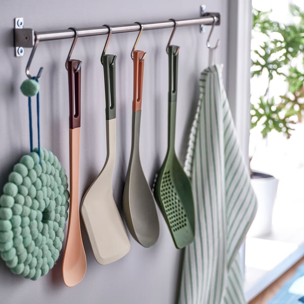 Kitchen utensils hang on hooks, featuring a wide-bladed spatula and green striped towel.