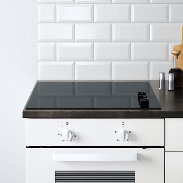 Modern kitchen setup with a white KNOXHULT modular stove and control knobs, featuring a sleek black glass induction hob.