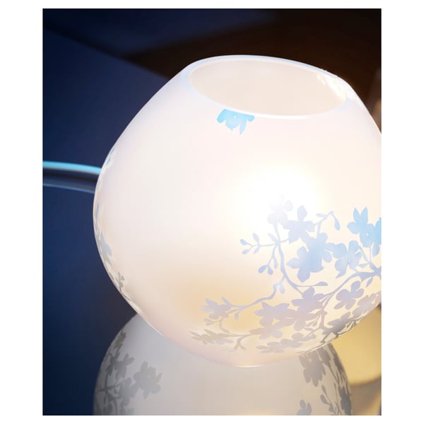 A small white table lamp with etched cherry blossoms that glows softly.