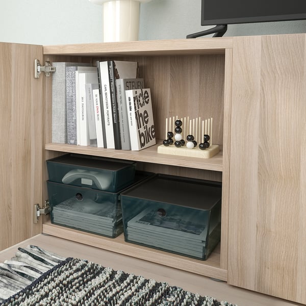 Wooden cabinet with glass drawers storing stationery and books, under flat-screen tv.
