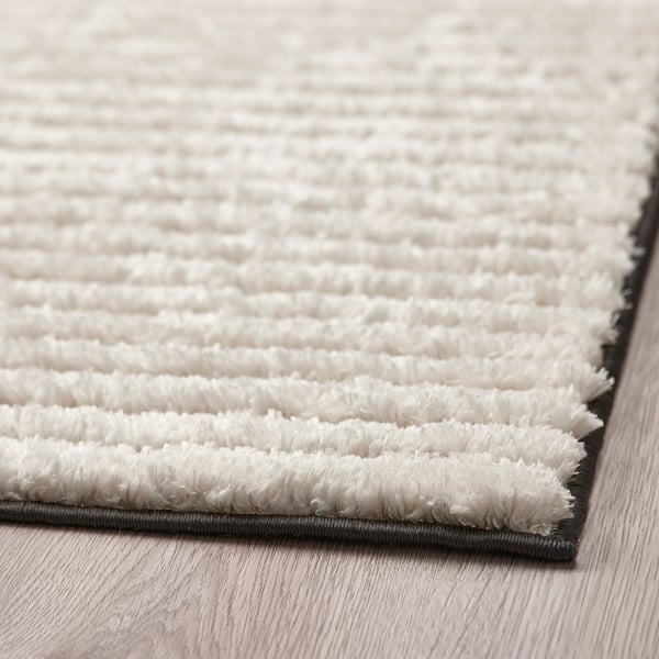 Close-up of a soft, textured rug with varying pile heights, placed on wooden flooring.