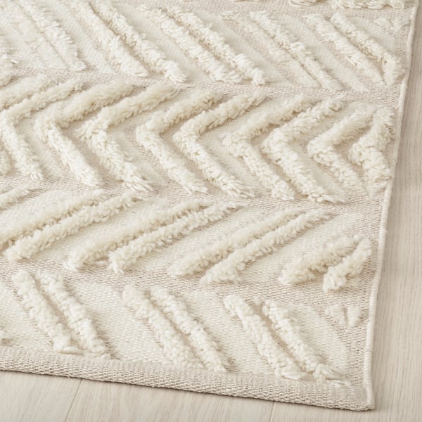 Soft, textured rug with geometric furrows, handcrafted from wool, beige tone.