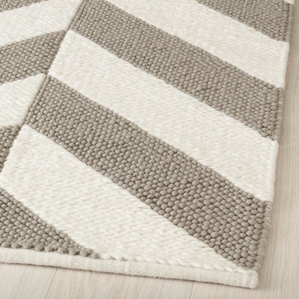 A handwoven wool rug with grey and beige stripes, highlighting its soft, high-quality texture.