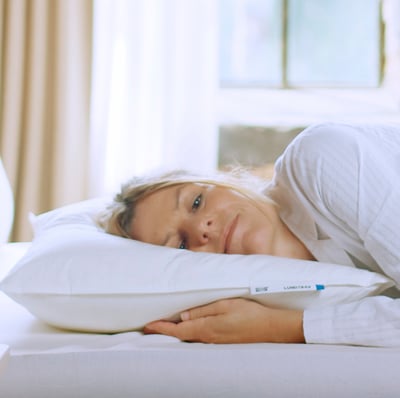 Person on soft LUNDTRAV feather pillow, ideal for side or back sleepers.