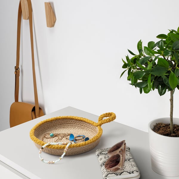 Jute baskets on table with jewellery and plant.