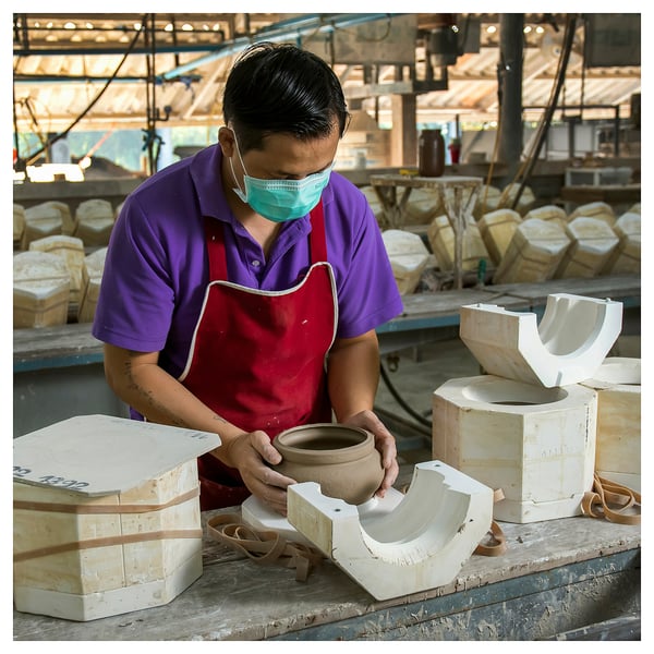 Person crafting a bowl at workshop bench.