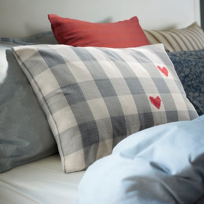 Chequered, grey-and-white pillow with red hearts, part of a set with varied colours and patterns.