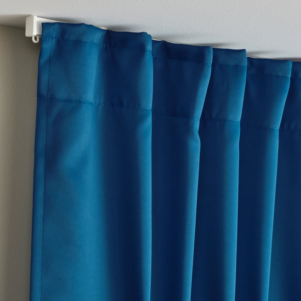 Blue curtains hang from white rod, blocking light. Drapery panels are sensed to be soft, provide privacy, and control room temperature.