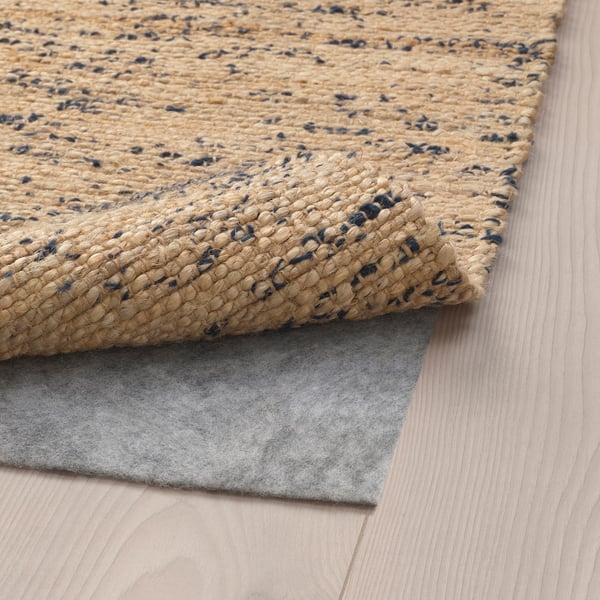 Hand-woven jute rug with wool accents, textured surface, anti-slip felt underside.