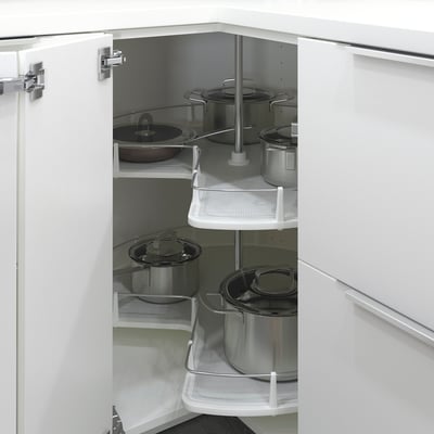 Open white kitchen cabinet displaying pots and pans on rotating shelves.