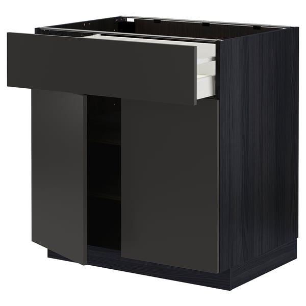 A black METOD kitchen cabinet with one drawer partially open, illustrating its storage space and pull-out design.