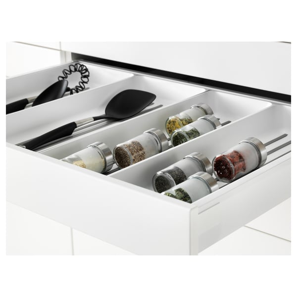 White kitchen drawer with spice jars and utensils, self-closing mechanism.