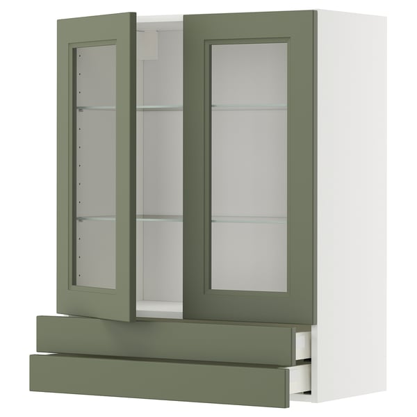 An ikea METOD kitchen cabinet. It is white with green-gray glass doors, frameless design, and two shelves.
