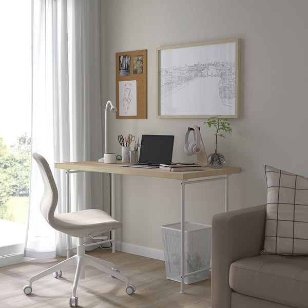 Minimalist home office with white desk, grey chair, and decor.