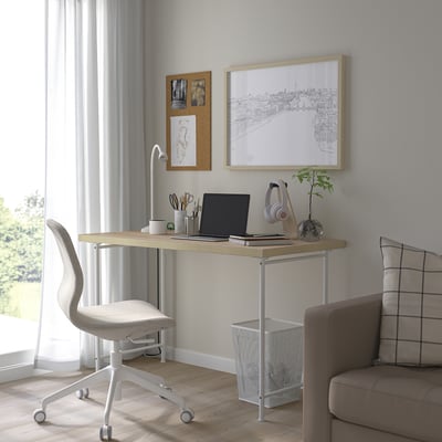 Minimalist home office with white desk, grey chair, and decor.