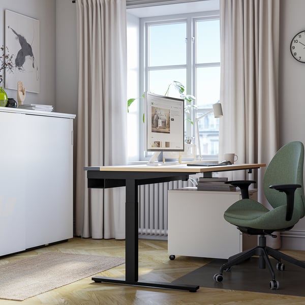 Minimalist office setup: adjustable MITTZON desk, green chair, computer, decor & natural light.