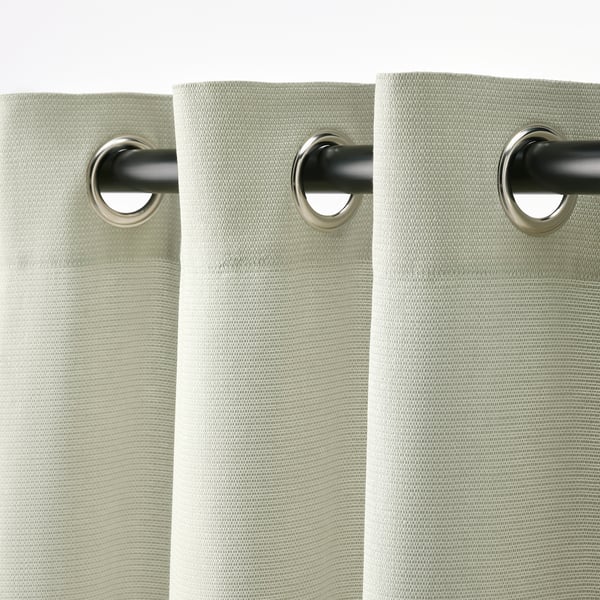 A pair of light green curtains with eyelets for rod hanging, designed to block light and offer privacy.