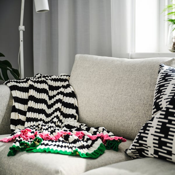 A cosy MOSSMOTT striped throw blanket on a couch, soft and recycled.