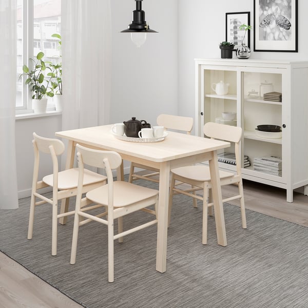 Wooden NORRÅKER dining set in bright room with window plants.