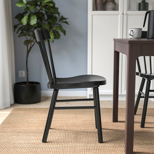 Black spindle chair with rounded shapes, perfect for relaxing around a table.