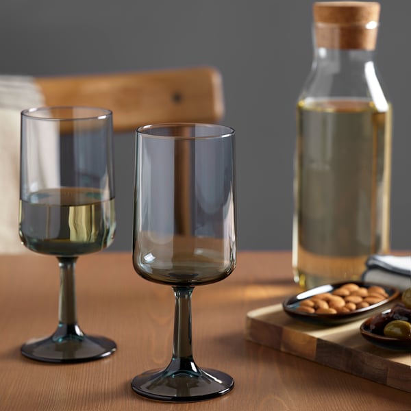 Grey wine glasses, carafe, and nuts on wooden table.