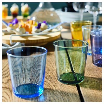 Vibrant blue and green glasses on a wooden table, perfect for lively table settings with friends.
