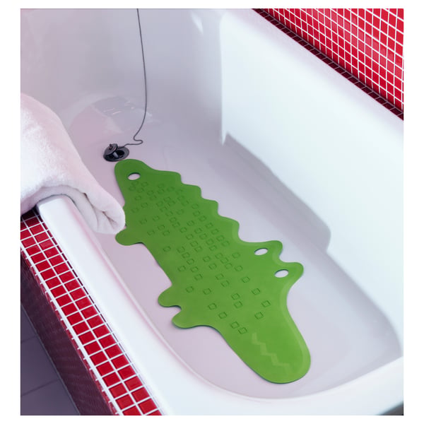 A green bathtub mat named PATRULL with a crocodile-like shape and suction cups for safety.