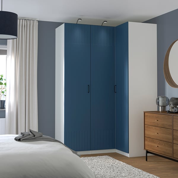 Modern bedroom with blue PAX wardrobe, wooden dresser, and gray-blue wall.