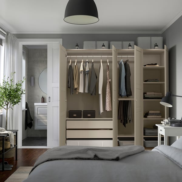 Modern bedroom with built-in wardrobe, clothes hangers, shelves, and drawers for organised storage. Grey-beige colour scheme.