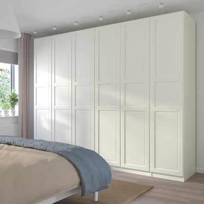 White PAX wardrobe with multiple compartments beside bed.