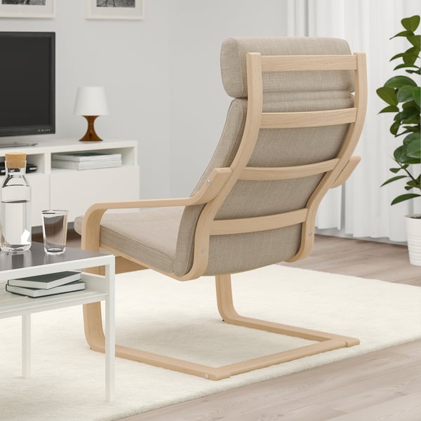 A beige armchair with wooden frame in a living room, offering neck support and comfortable resilience.