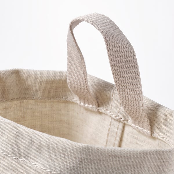 Close-up of a stylish, beige woven tote bag with strong handles, showcasing its quality craftsmanship.