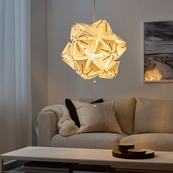 Geometric pendant lamp above beige sofa with throw and striped pillows.