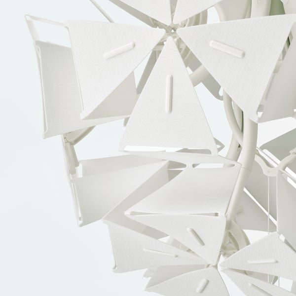 Modern white pendant lamp with triangular shades, intricate design, casting soft light and shadows.