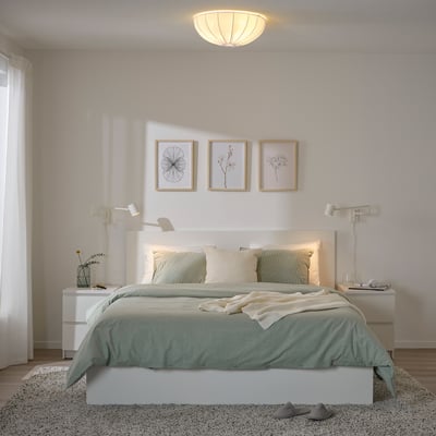 Minimalist bedroom with REGNSKUR lamp, striped bedding, wall lights, art prints, sheer curtains, rug.