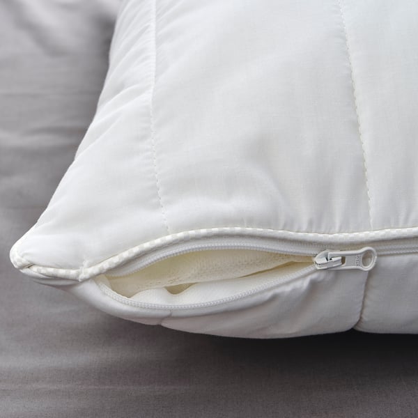 Close-up of high-quality white pillow, zip open, revealing soft stuffing, on a bed.