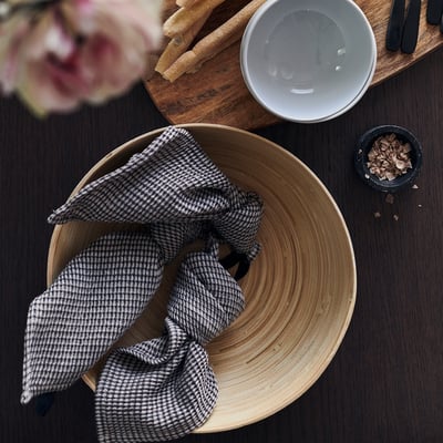 Bamboo bowl with napkin, chopsticks, and sauce.